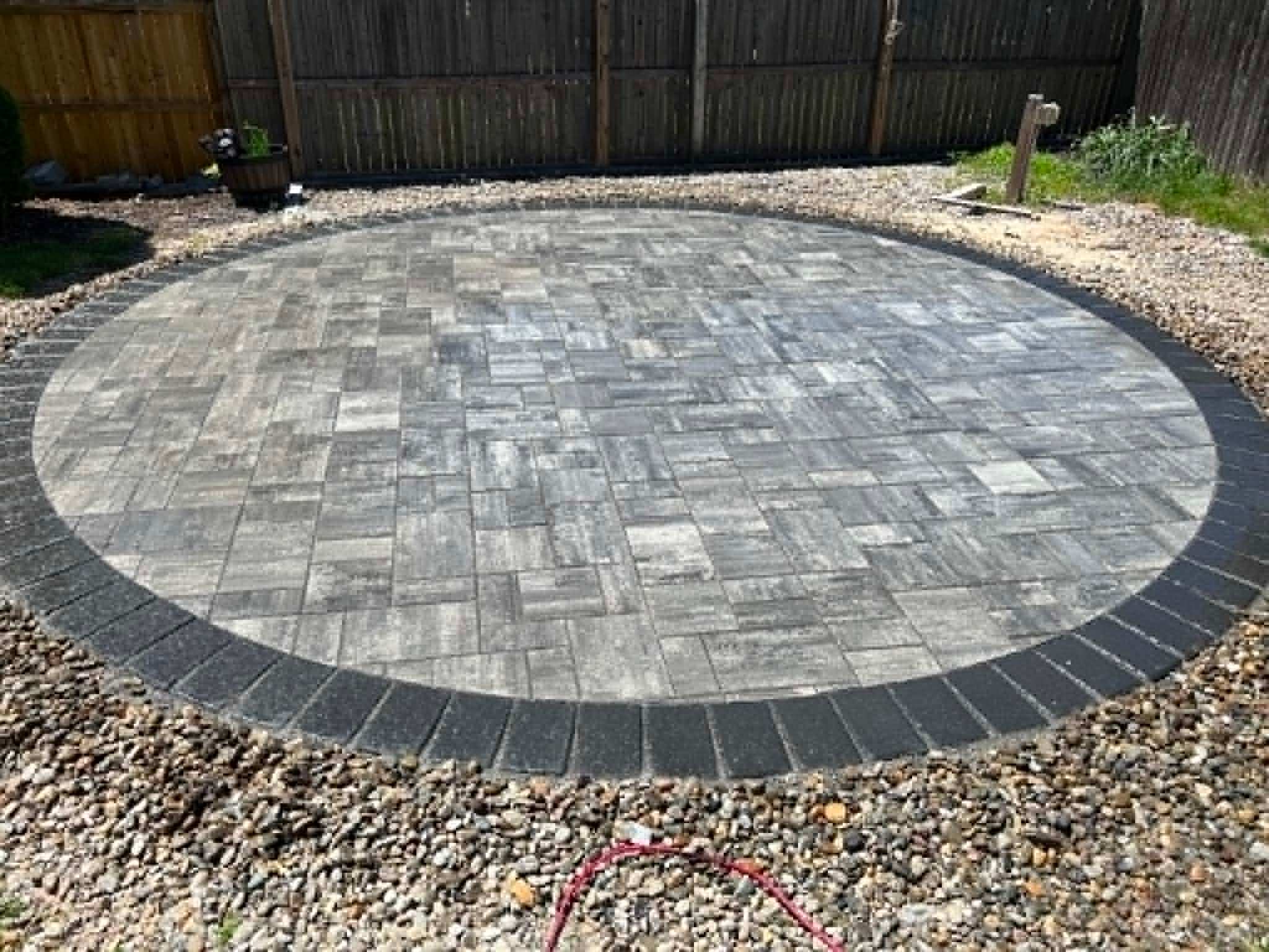 Circular paver patio with clean joint sand and sharp edge restraint after maintenance service