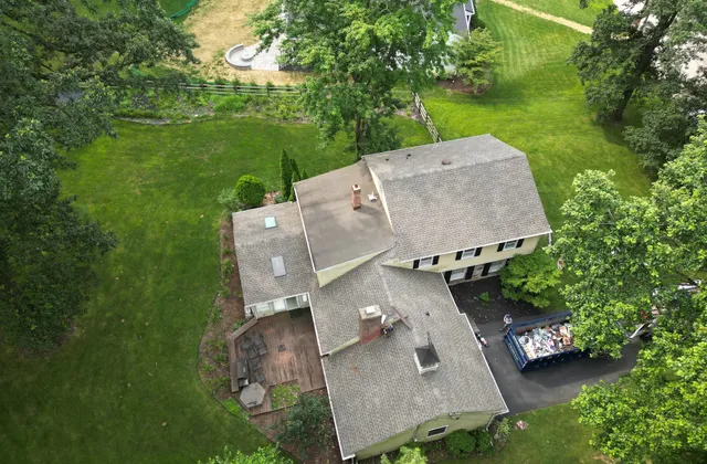 Aerial view of a New Jersey split-level home with a lower flat-roofed wing meeting the main pitched roof