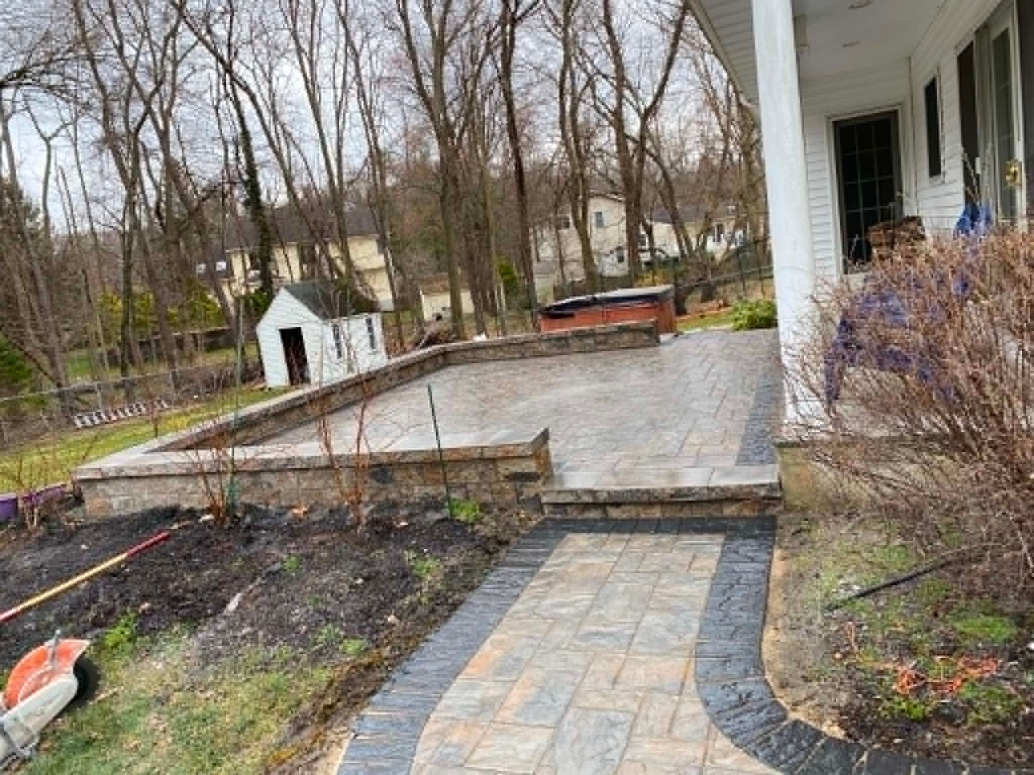 Paver patio with retaining wall built around a backyard hot tub, New Jersey