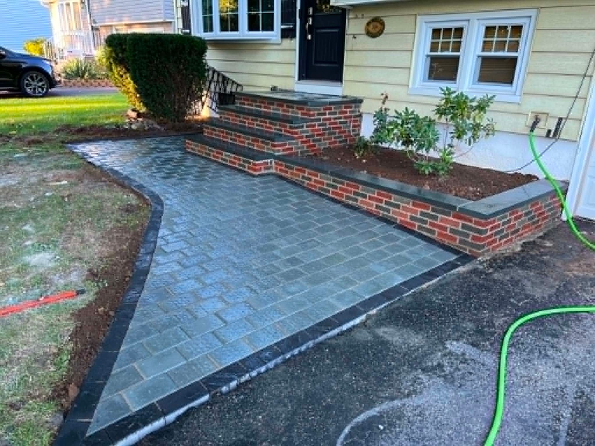 Curved paver walkway with brick steps and sitting wall leading to the front entry, New Jersey